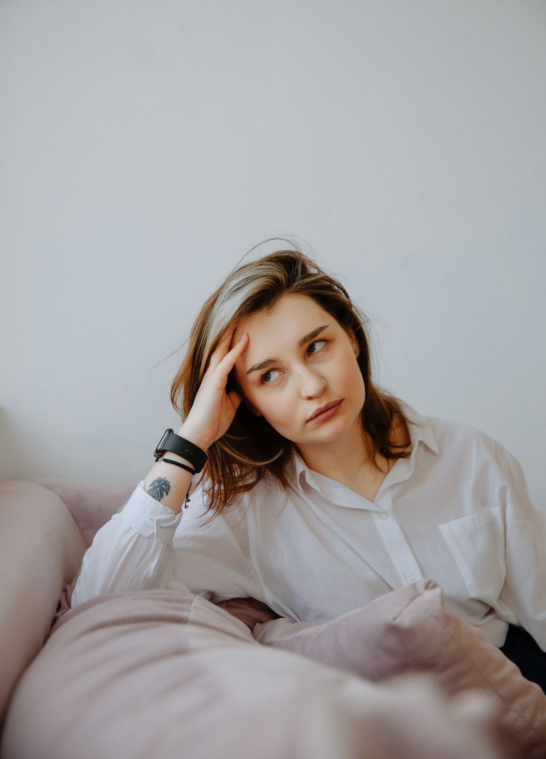 Vrouw zit op de bank met haar hand tegen haar hoofd door stress en zorgen.