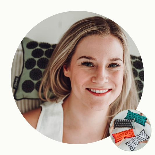 Lachende vrouw ontspant met een groen Flowee spijkerkussen, verkrijgbaar in verschillende kleuren.