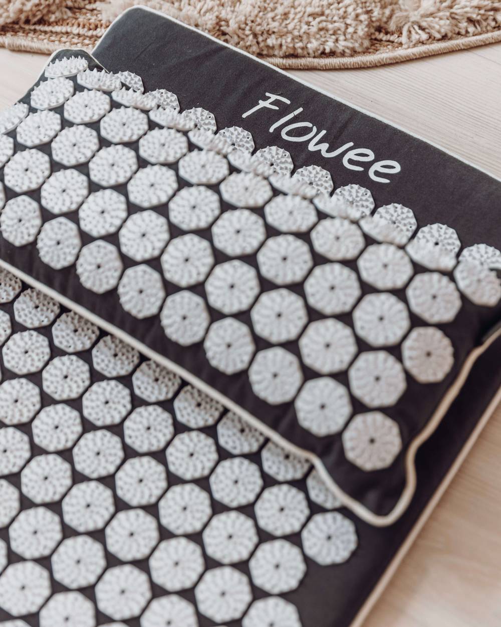 Grijze spijkermat set met witte spijkers van Flowee op een houten vloer.