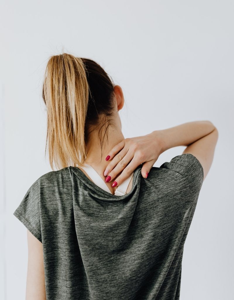 Vrouw houdt haar nek vast bij nek- en schouderklachten die met acupressuur of acupunctuur behandeld kunnen worden.