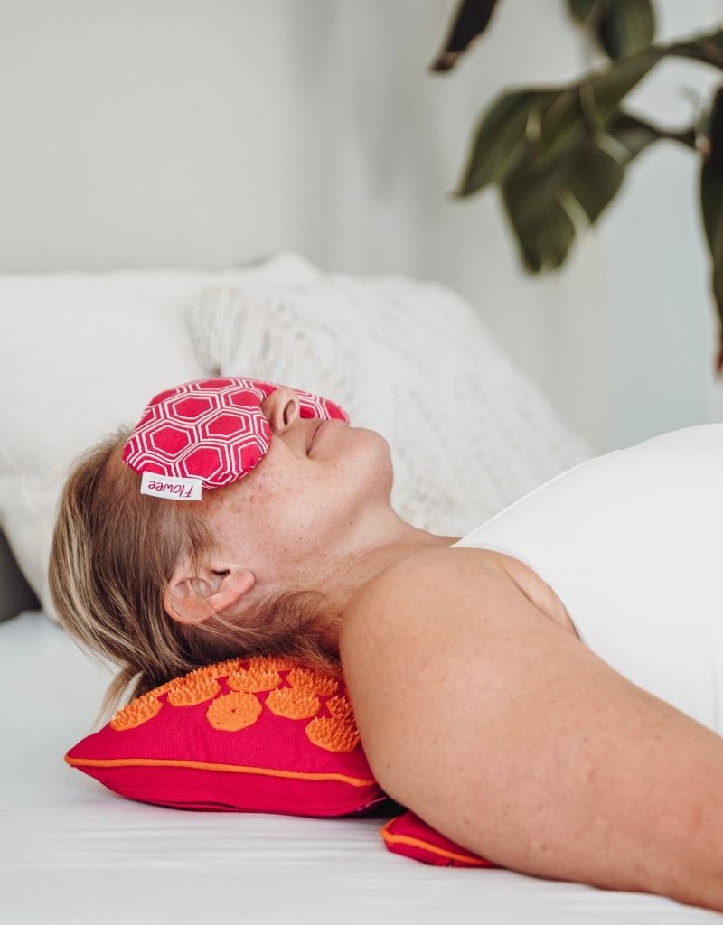 Vrouw geniet van ontspanning tijdens de feestdagen met een Flowee spijkerkussen en oogkussen.