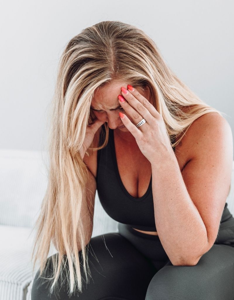 Vrouw houdt haar hoofd vast bij stress en spanning door PTSS-klachten.