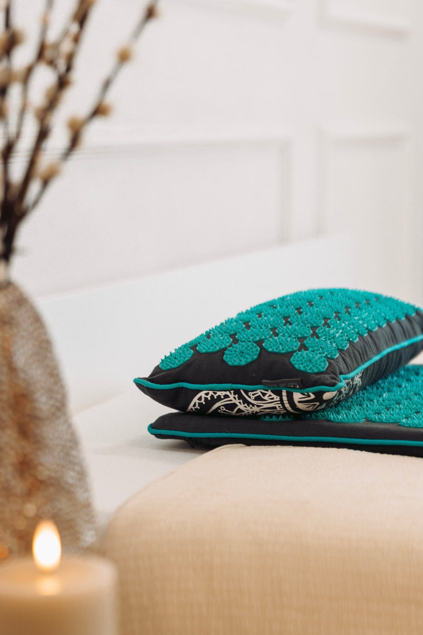 Een spijkermat met spijkerkussen in grijs met zeegroen ligt op een bed met accessoires op de voorgrond