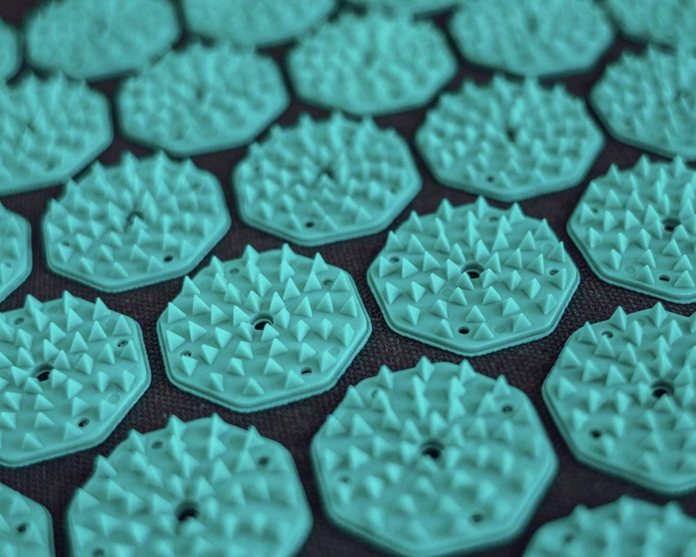 De details van een grijze spijkermat met zeegroene spikes